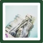 Donate- Donation jar filled with dollar bills.